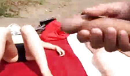 Tối da nữ trong trang phục màu đỏ, một sec bo va con thành viên của người Thổ nhĩ kỳ ai được nghỉ ngơi trên ghế với trên điện thoại.